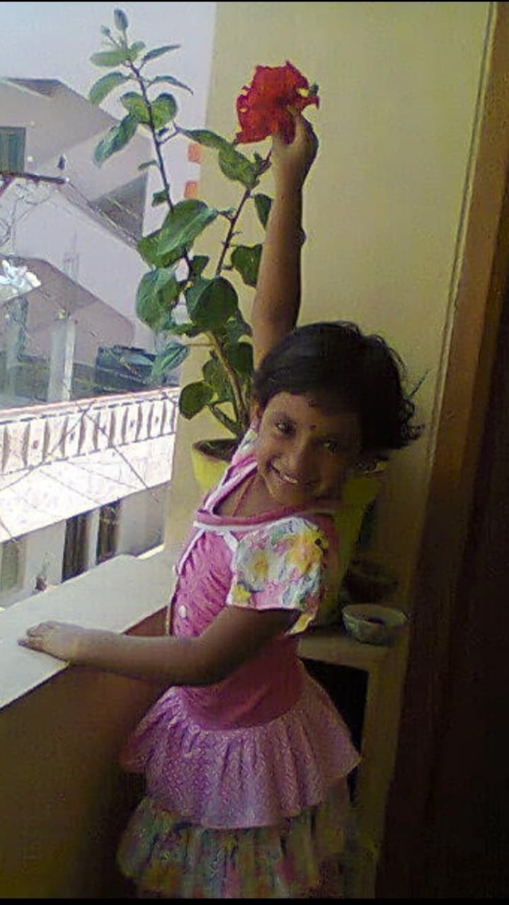 Spandana Reddy as a child, reaching for a hibiscus